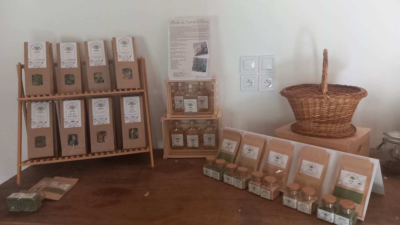 Stand de vente : présentoirs en bois garnis de tisanes, pots et sirops, panier en osier